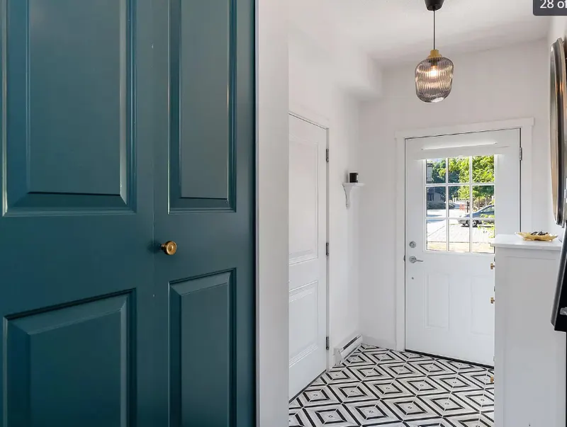 Entryway by PS Tiling, photo from a Google review: black and white patterned floor tile beside teal doors, finished.