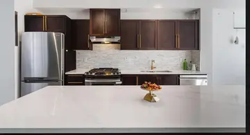 Kitchen renovation by PS Tiling, photo from a Google review: dark cabinets, white quartz counters and a grey mosaic backsplash, finished.