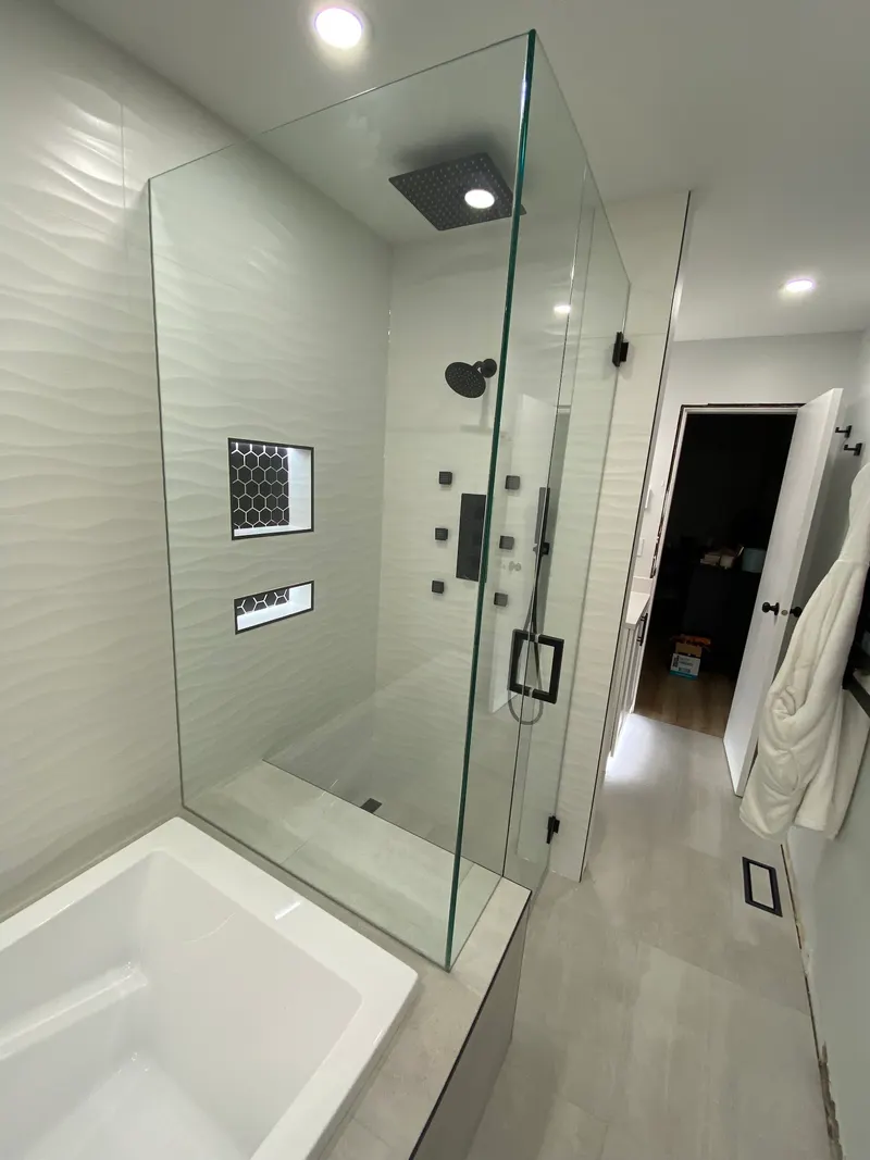 Bathroom renovation by PS Tiling, photo from a Google review: walk-in shower with white wave-texture tile, black rain head and hexagon mosaic niches, finished.