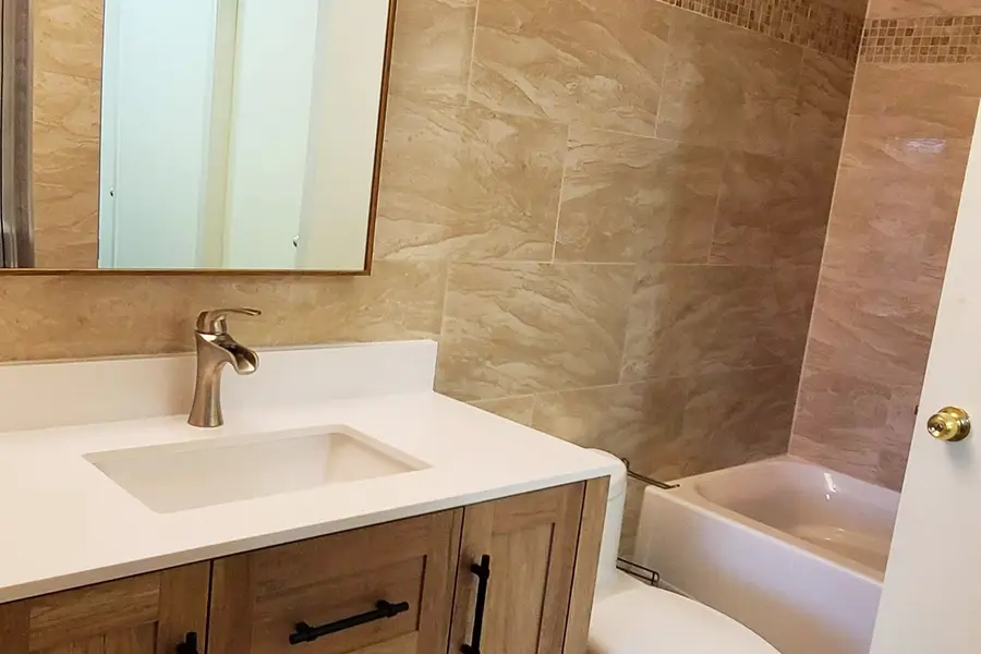 Bathroom renovation in Port Coquitlam by PS Tiling: overview of the bathroom with wood vanity, toilet and tiled tub, finished.