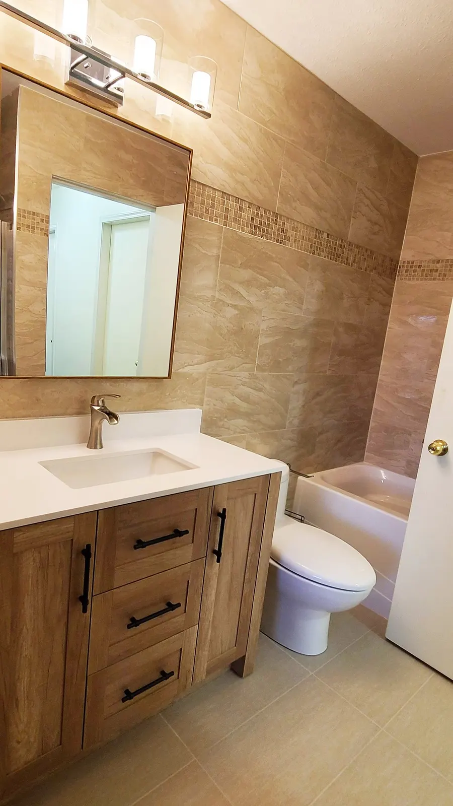 Bathroom renovation in Port Coquitlam by PS Tiling: overview of the bathroom with wood vanity, toilet and tiled tub, finished.