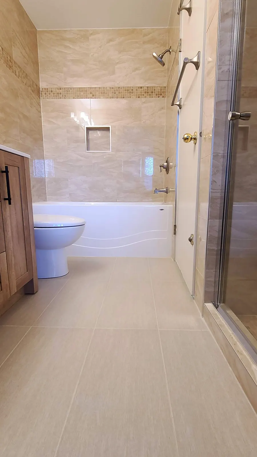 Bathroom renovation in Port Coquitlam by PS Tiling: view through the doorway to the vanity and tiled shower, finished.