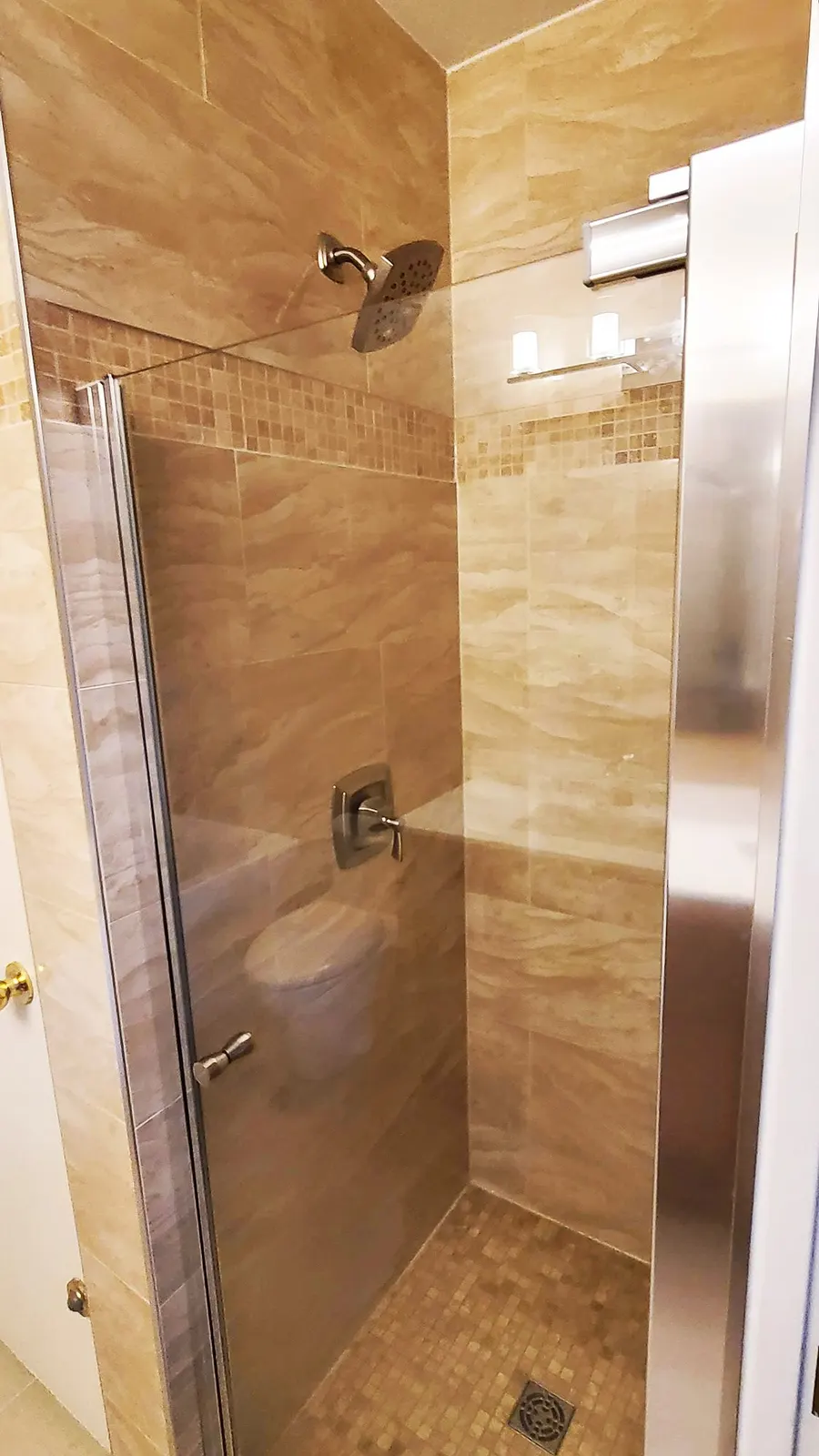 Bathroom renovation in Port Coquitlam by PS Tiling: framed glass shower stall with a mosaic tile floor, finished.