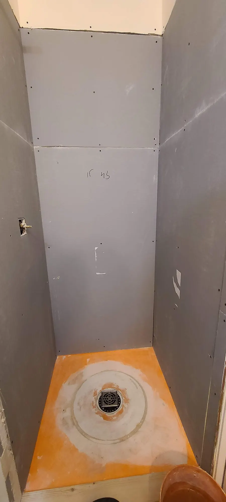 Bathroom renovation in Port Coquitlam by PS Tiling: orange Kerdi waterproofing membrane on the shower pan and drain, before tile, during waterproofing.