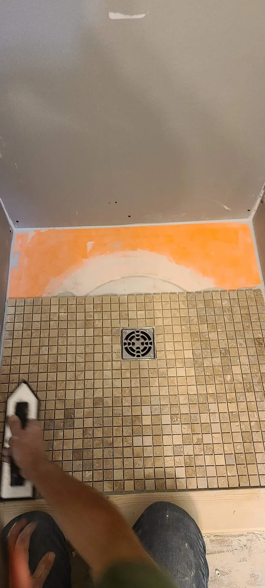Bathroom renovation in Port Coquitlam by PS Tiling: mosaic tile going onto the shower floor over the Kerdi membrane, during shower floor tiling.