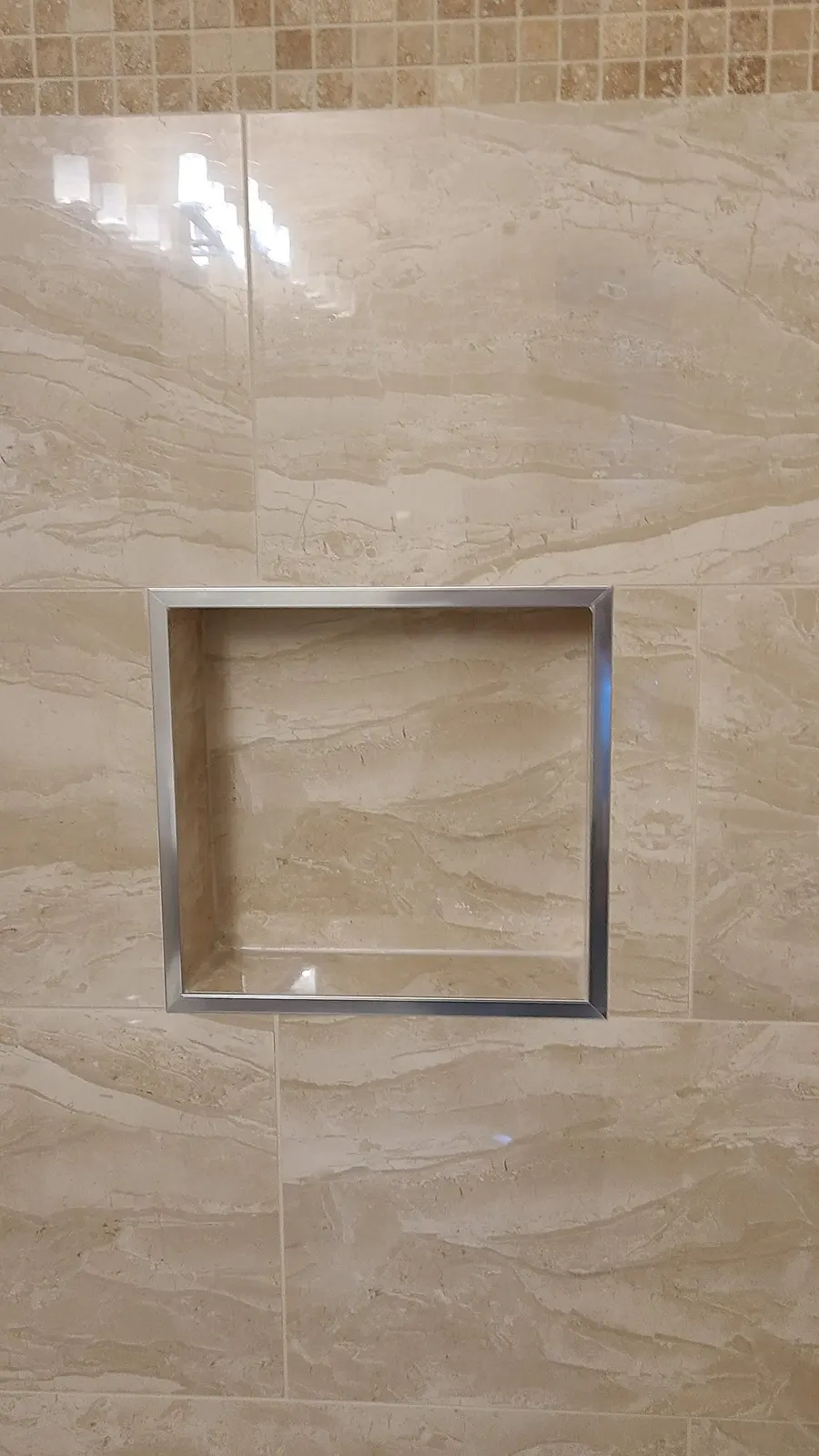 Bathroom renovation in Port Coquitlam by PS Tiling: recessed niche with mosaic accent band in beige porcelain, detail.
