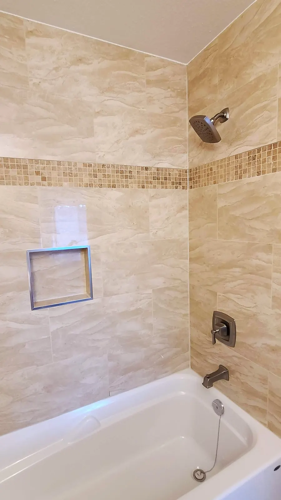 Bathroom renovation in Port Coquitlam by PS Tiling: tub surround with recessed niche and mosaic accent band, finished.