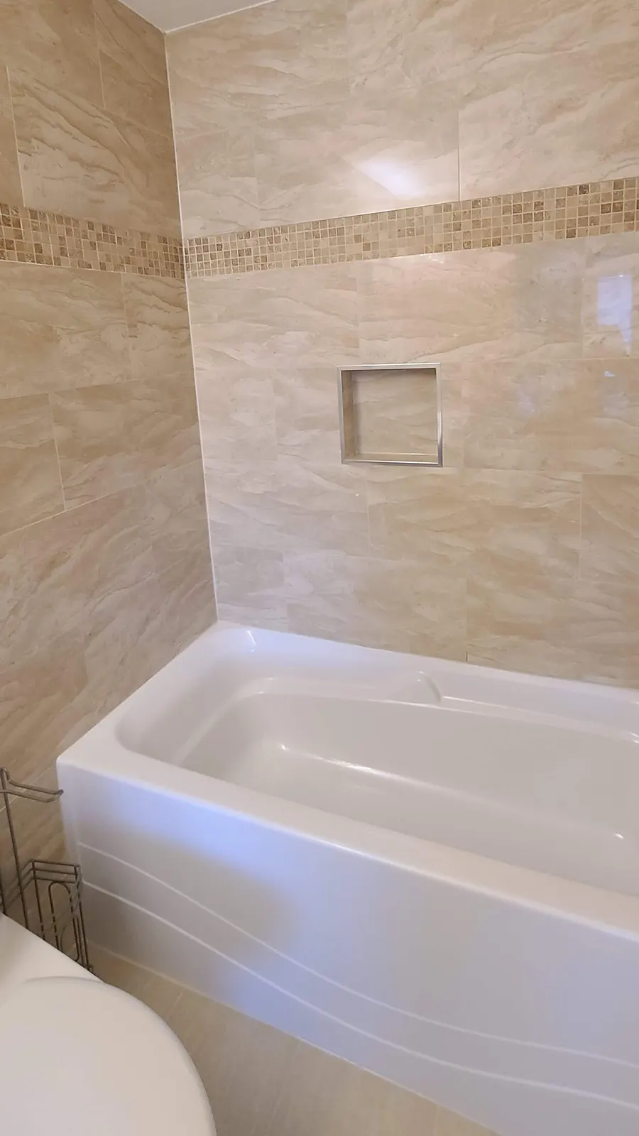 Bathroom renovation in Port Coquitlam by PS Tiling: white bathtub with beige marble-look tile surround, finished.