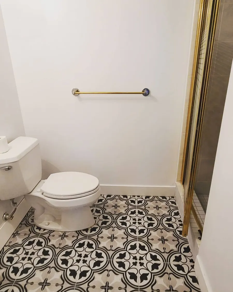 Condo bathroom renovation in Fairview, Vancouver by PS Tiling: black-and-white patterned floor tile with toilet and brushed gold grab bar, finished.