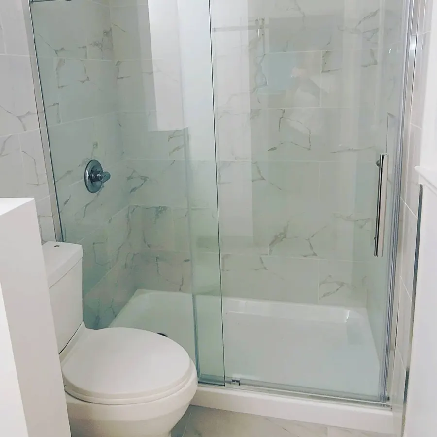 Condo bathroom renovation in Fairview, Vancouver by PS Tiling: marble-look shower with sliding glass door and toilet, finished.