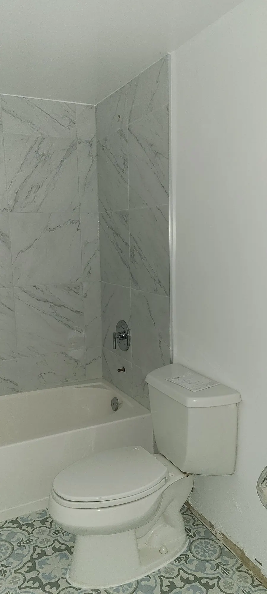 Condo bathroom renovation in Fairview, Vancouver by PS Tiling: marble-look tub surround with blue patterned floor, finished.