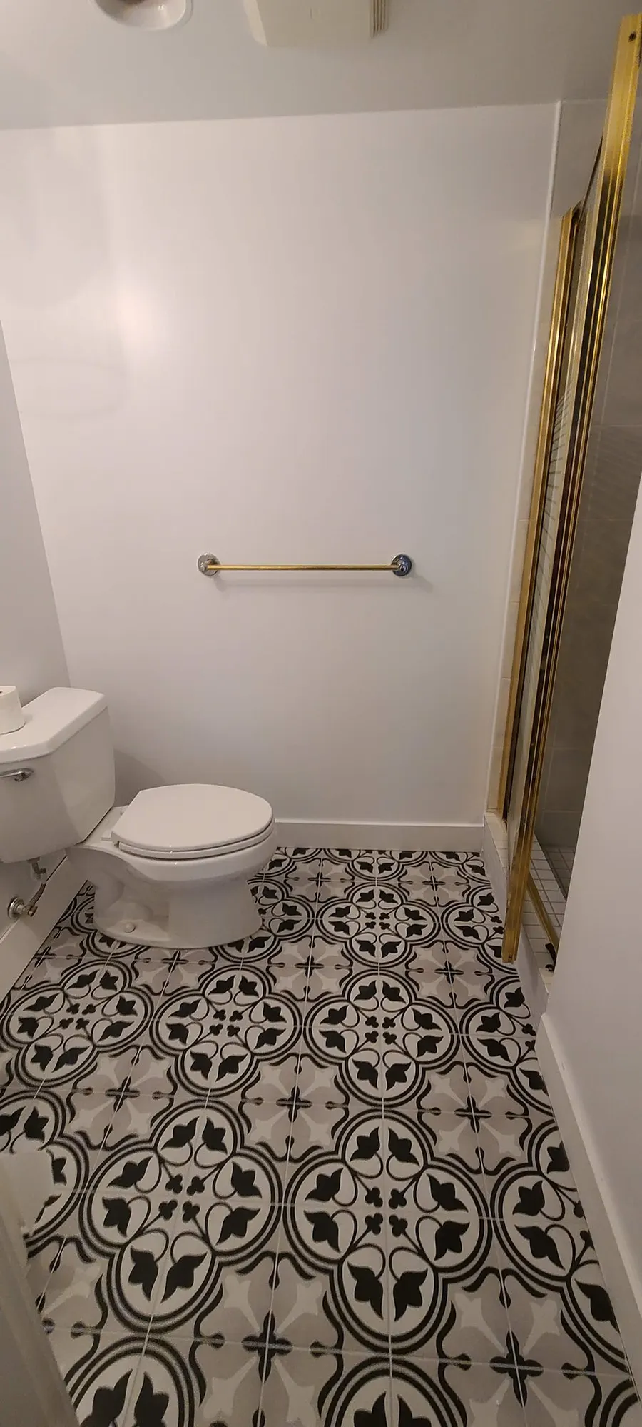 Condo bathroom renovation in Fairview, Vancouver by PS Tiling: black-and-white patterned floor with toilet and brushed gold grab bar, finished.