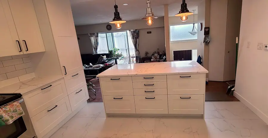 Kitchen renovation in Port Moody by PS Tiling: wide view of the white quartz island opening to the living room, finished.