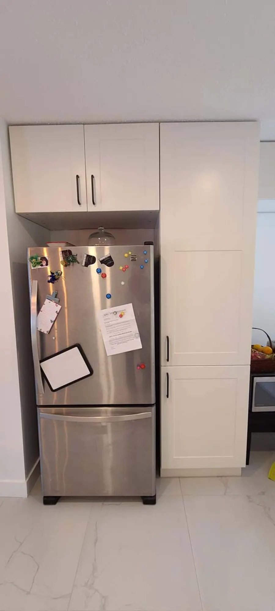 Kitchen renovation in Port Moody by PS Tiling: stainless fridge framed by white shaker cabinets, finished.