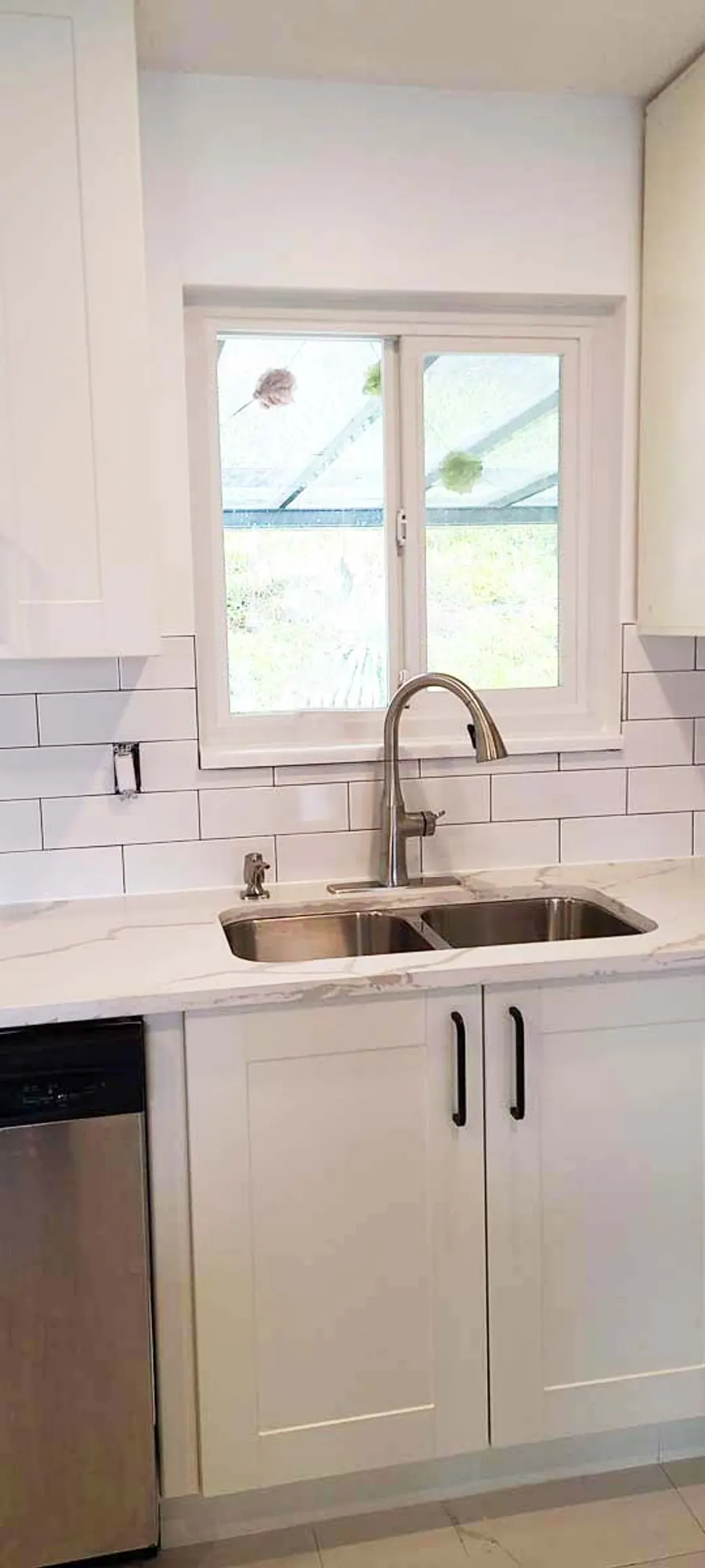 Kitchen renovation in Port Moody by PS Tiling: undermount sink under the window with subway-tile backsplash and white cabinets, finished.
