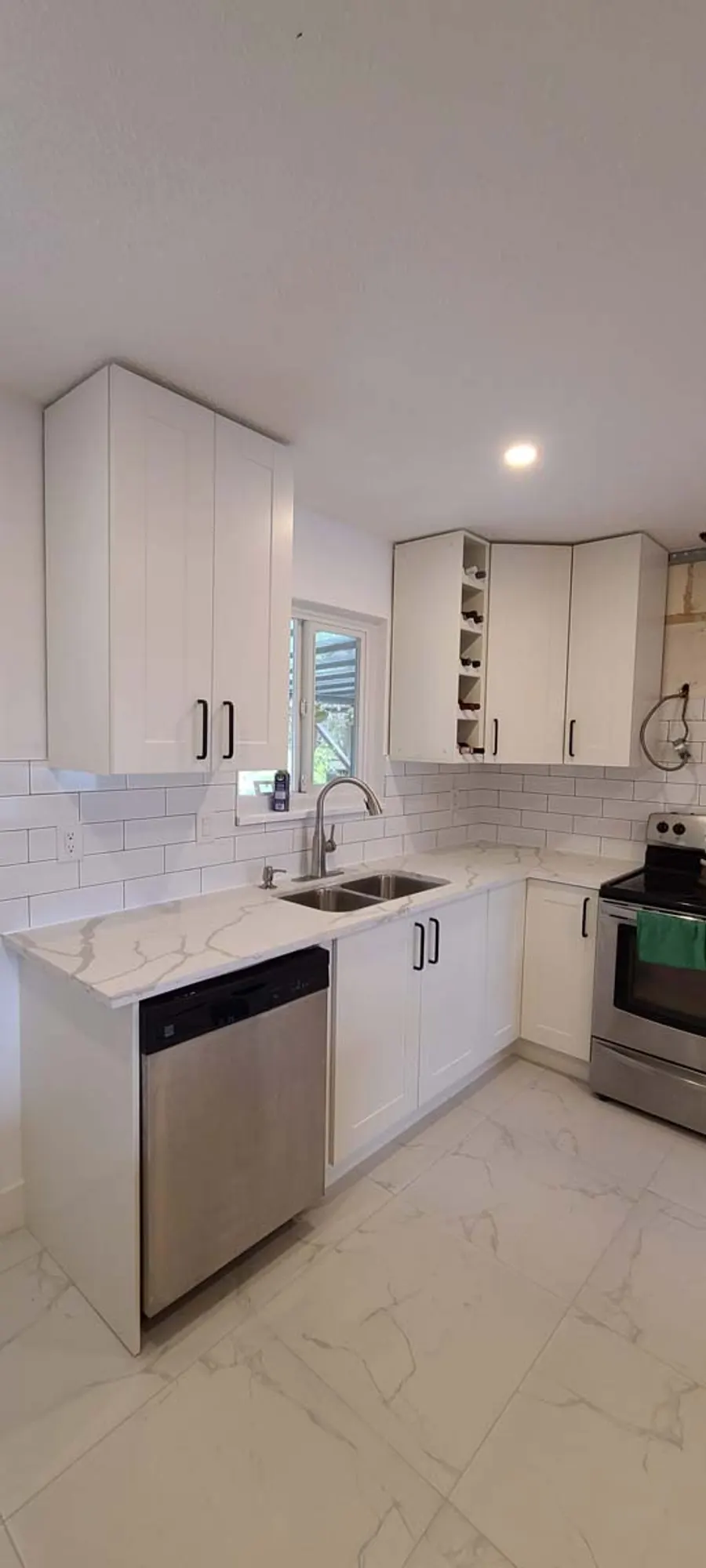 Kitchen renovation in Port Moody by PS Tiling: white cabinets, dishwasher and range wall with subway backsplash, finished.