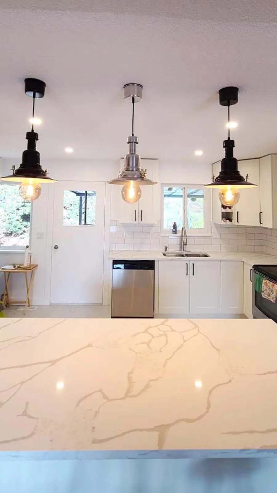 Kitchen renovation in Port Moody by PS Tiling: white quartz island top under three pendant lights, finished.