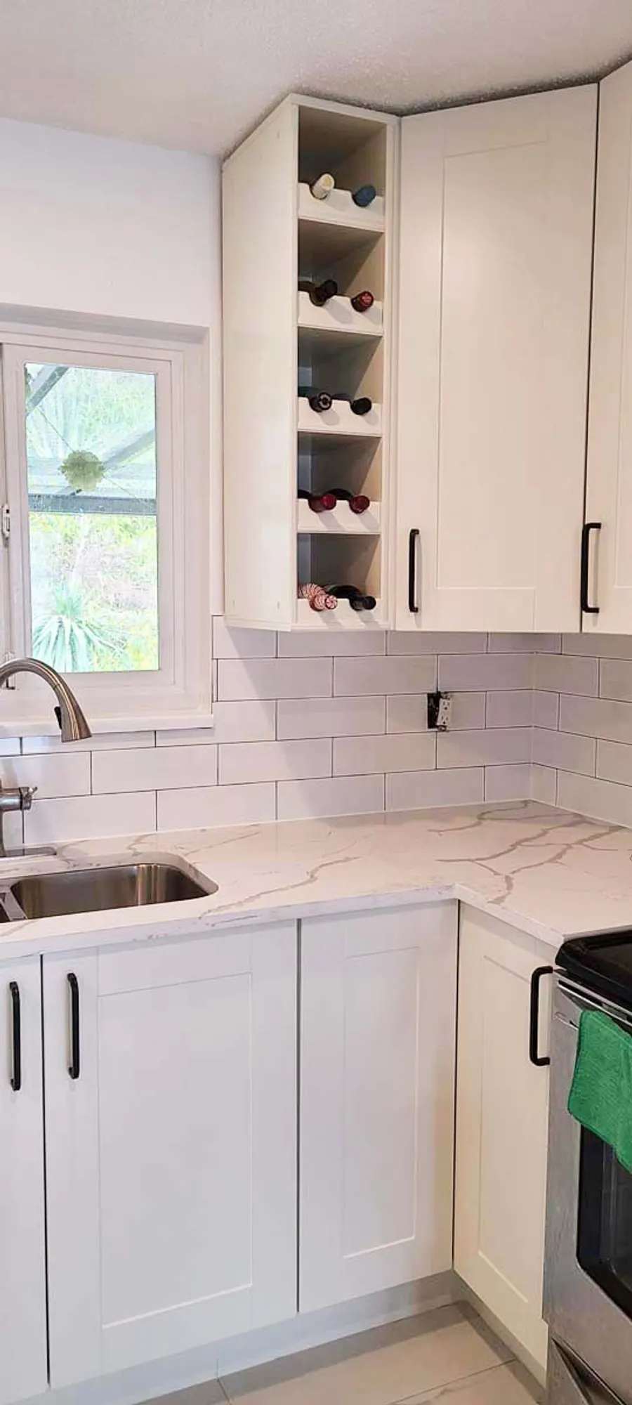 Kitchen renovation in Port Moody by PS Tiling: white shaker cabinets with a glass-front upper and subway backsplash, finished.