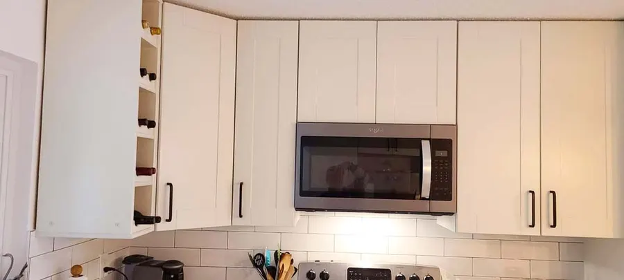Kitchen renovation in Port Moody by PS Tiling: white upper cabinets and microwave over subway backsplash, finished.