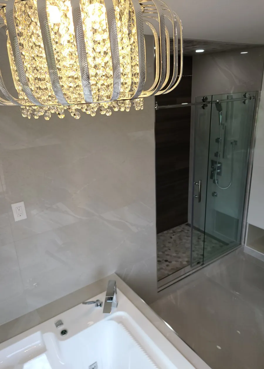 Master bathroom renovation in Burquitlam, Coquitlam by PS Tiling: crystal chandelier over the tub with the glass shower behind, detail.