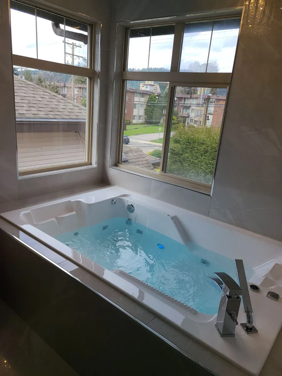 Master bathroom renovation in Burquitlam, Coquitlam by PS Tiling: jacuzzi tub with chrome waterfall filler by the window, finished.