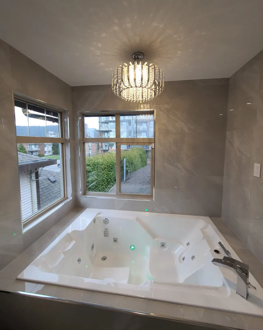 Master bathroom renovation in Burquitlam, Coquitlam by PS Tiling: jacuzzi tub with jets and chrome filler under the chandelier, detail.