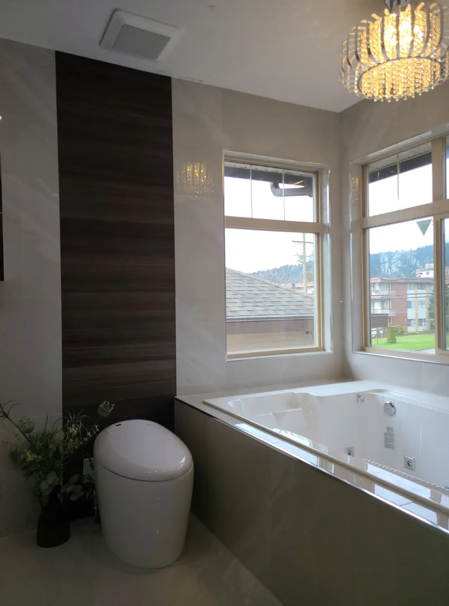 Master bathroom renovation in Burquitlam, Coquitlam by PS Tiling: smart toilet and jacuzzi tub with the wood-look accent wall and chandelier, finished.