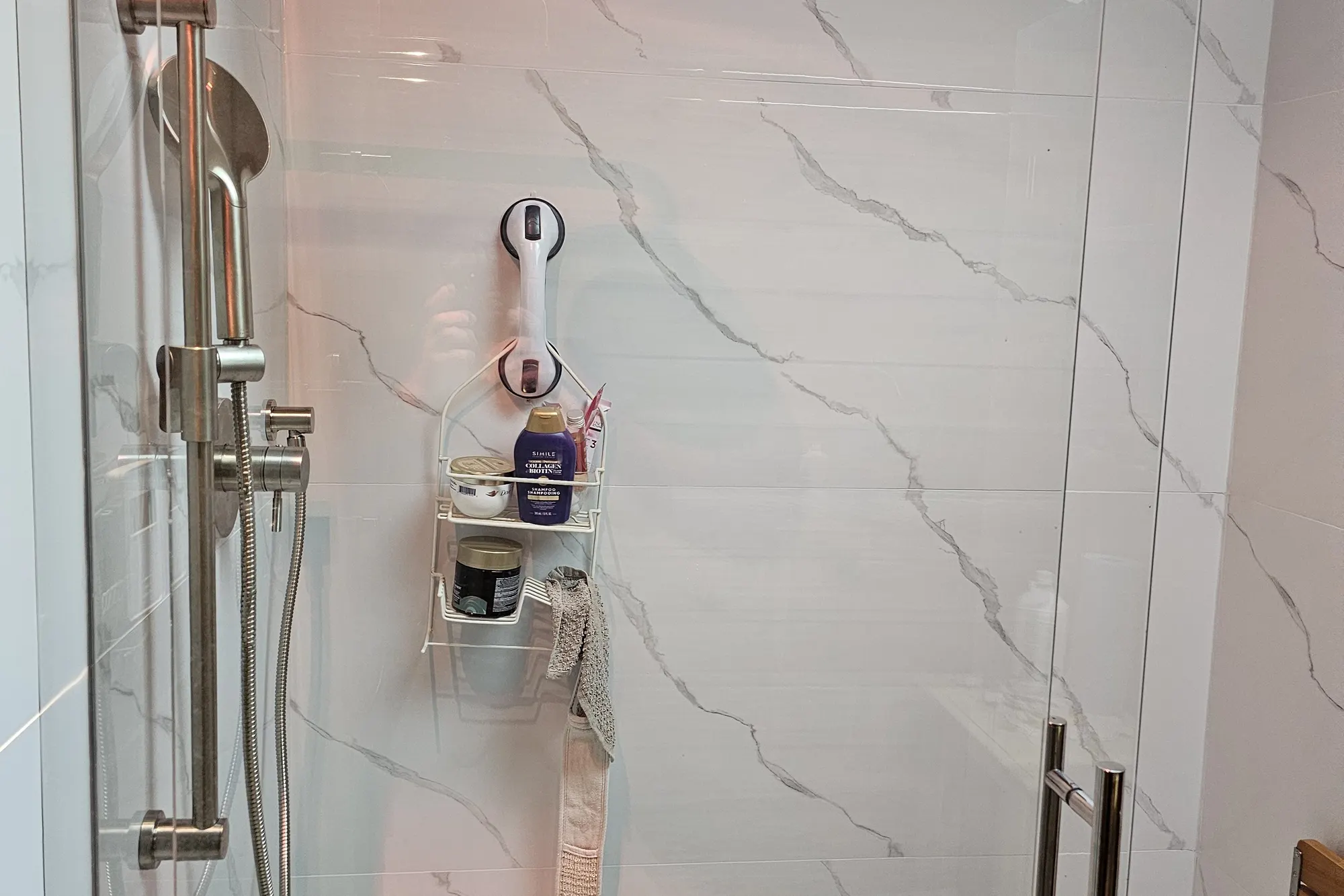 Shower renovation in Fort Langley by PS Tiling: frameless glass shower door with chrome handle and marble-look porcelain walls, finished.
