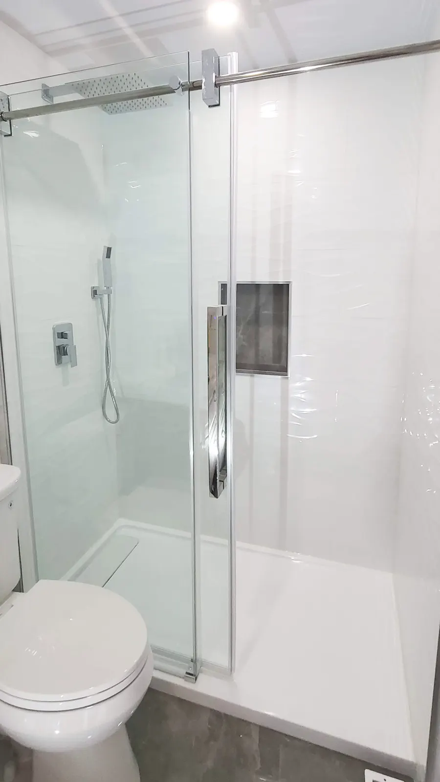Tub-to-shower conversion in Coquitlam by PS Tiling: frameless sliding glass walk-in shower where the tub was, finished.