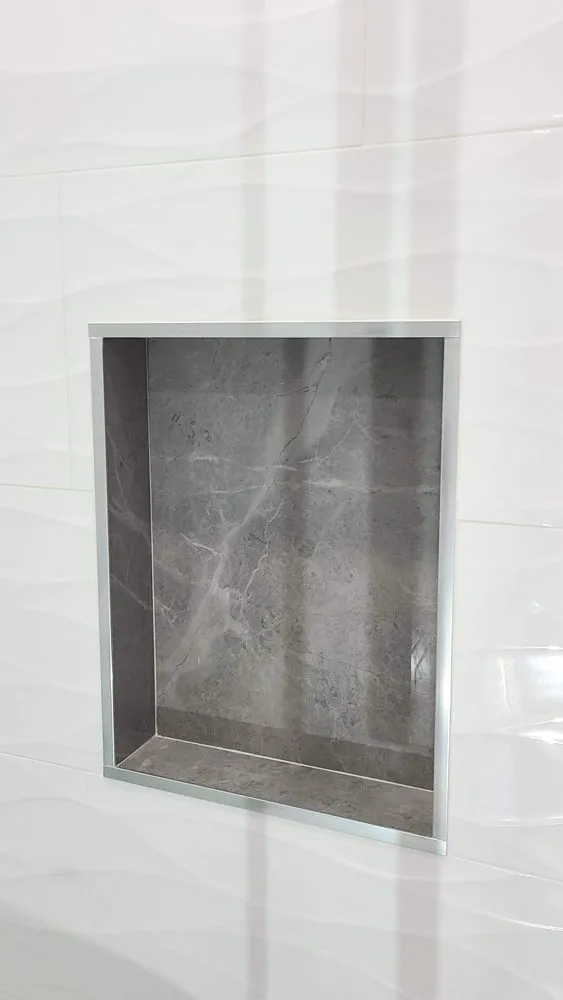 Tub-to-shower conversion in Coquitlam by PS Tiling, a recessed niche in grey marble-look tile with a glass shelf, finished.