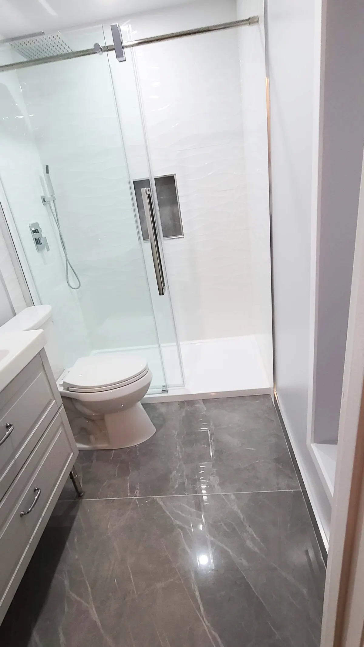 Tub-to-shower conversion in Coquitlam by PS Tiling: walk-in shower overview with white wave tile and grey floor, finished.