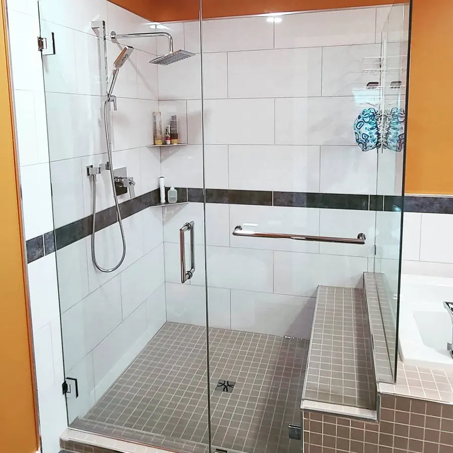 Shower renovation in Delta by PS Tiling: frameless glass shower with tiled bench, white tile and a black accent band, finished.